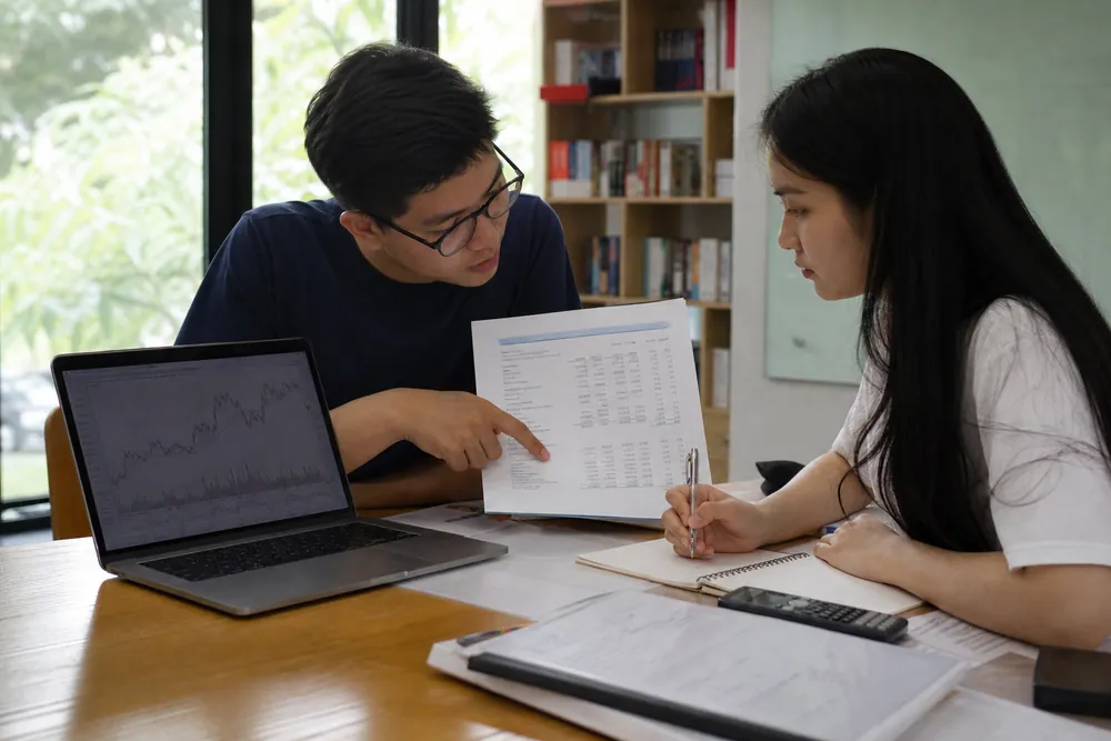 Hai sinh viên Việt Nam cùng phân tích báo cáo tài chính và biểu đồ doanh nghiệp trên bàn học
